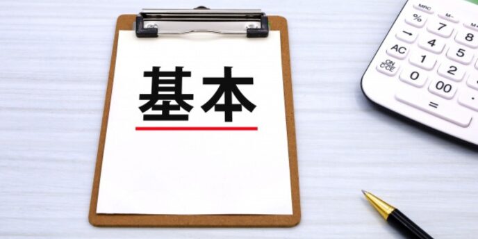 白い用紙に赤線付きで「基本」と書かれたメモがクリップボードに挟まれており、右に電卓とペンが置かれている