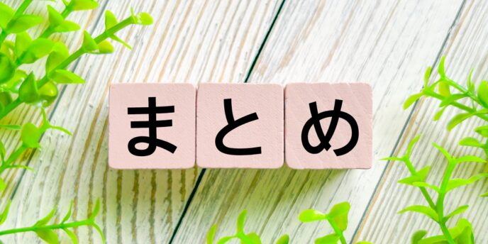 木目テーブル上に置いた「まとめ」の木製ブロックとグリーン