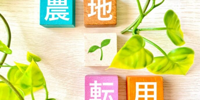 「農地転用」と書かれたカラフルな木製ブロックと若葉のイメージ