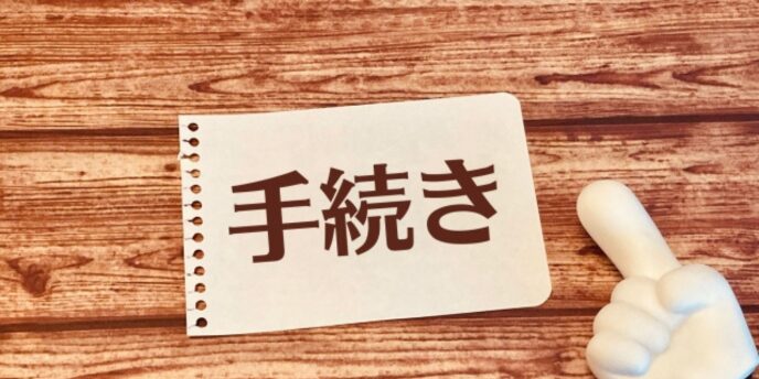 「手続き」と書かれた紙と親指を立てたサインの置物のイメージ