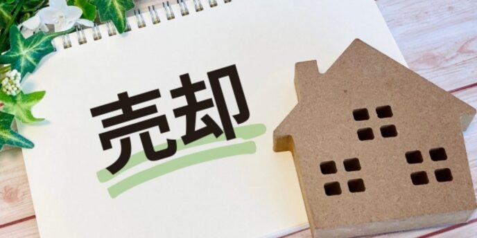 不動産の売却を表すノートと家の模型のイメージ