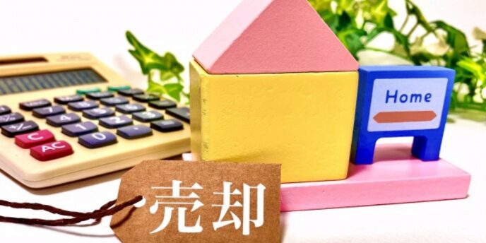 家の模型と電卓、「売却」のタグが添えられた不動産売却のイメージ
