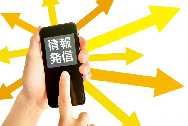 情報発信する携帯電話を持つ手元