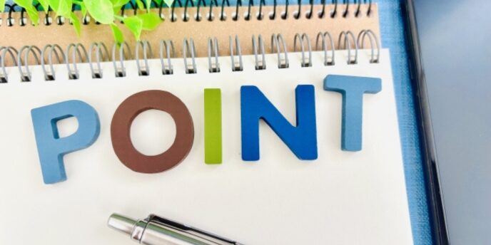 「POINT」と並べられたカラフルな文字とメモ、ペンのあるデスク上のイメージ
