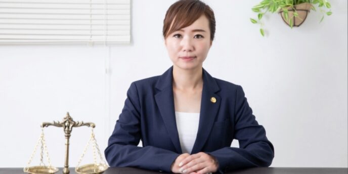 法律を象徴する天秤とともに机に座る女性弁護士のポートレート