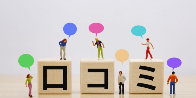 ブロックに「口コミ」と書かれた文字と、上に立つ人形がレビューを表現したイメージ