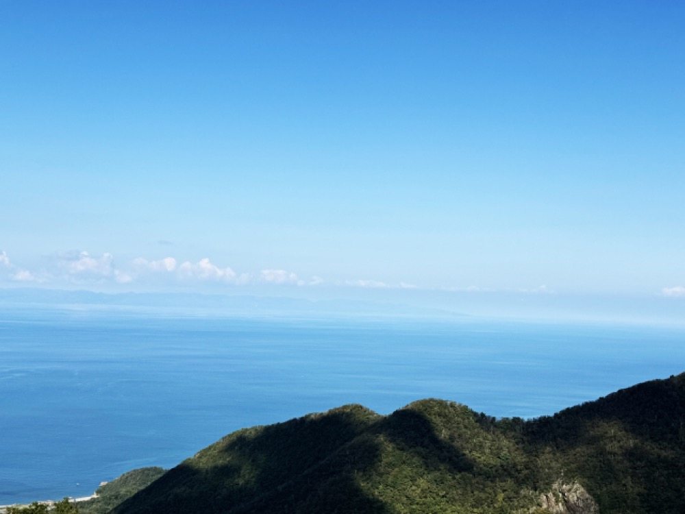 山並みの先に広がる青い海と空