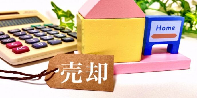 売却と書かれたタグが家の模型と電卓のそばに置かれているイメージ