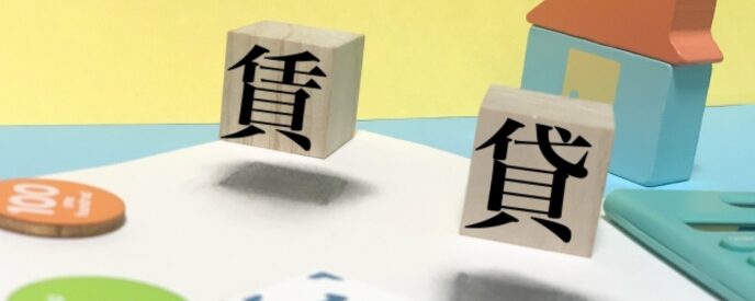 「賃貸」の漢字が書かれた木製サイコロと家の模型