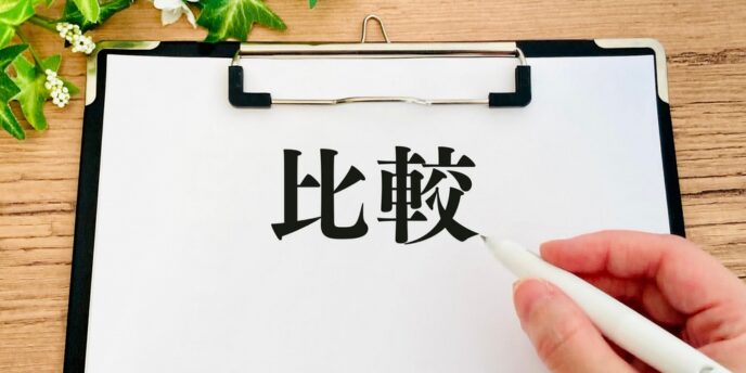 クリップボードの用紙に「比較」と書き込む手元