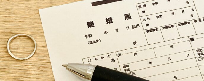 離婚届の書類と外した結婚指輪、黒いペンが置かれた書類シーン
