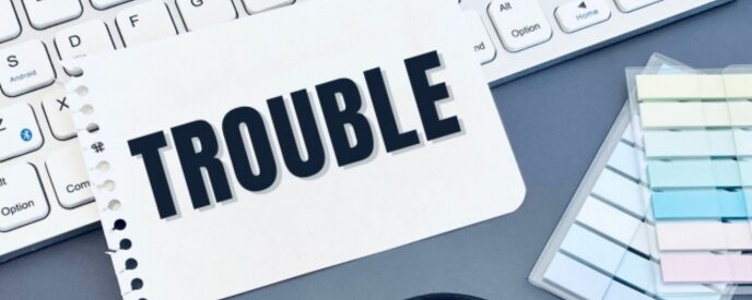 「TROUBLE」の文字とキーボード、付箋のあるオフィス風景