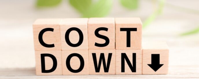 「COST DOWN」と書かれた積み木と下向き矢印の写真。