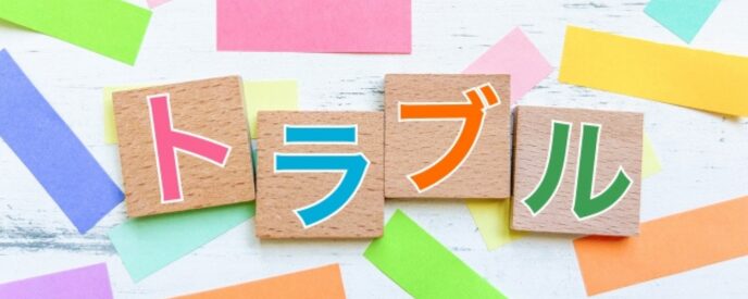カラフルな背景に「トラブル」と書かれた木製ブロックが並ぶ