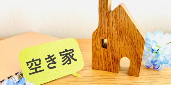 木製の家の模型と「空き家」の吹き出しが置かれたイメージ