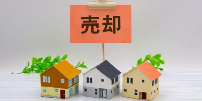 売却と書かれた札の下に3軒の住宅模型が並べられている不動産売却イメージの画像